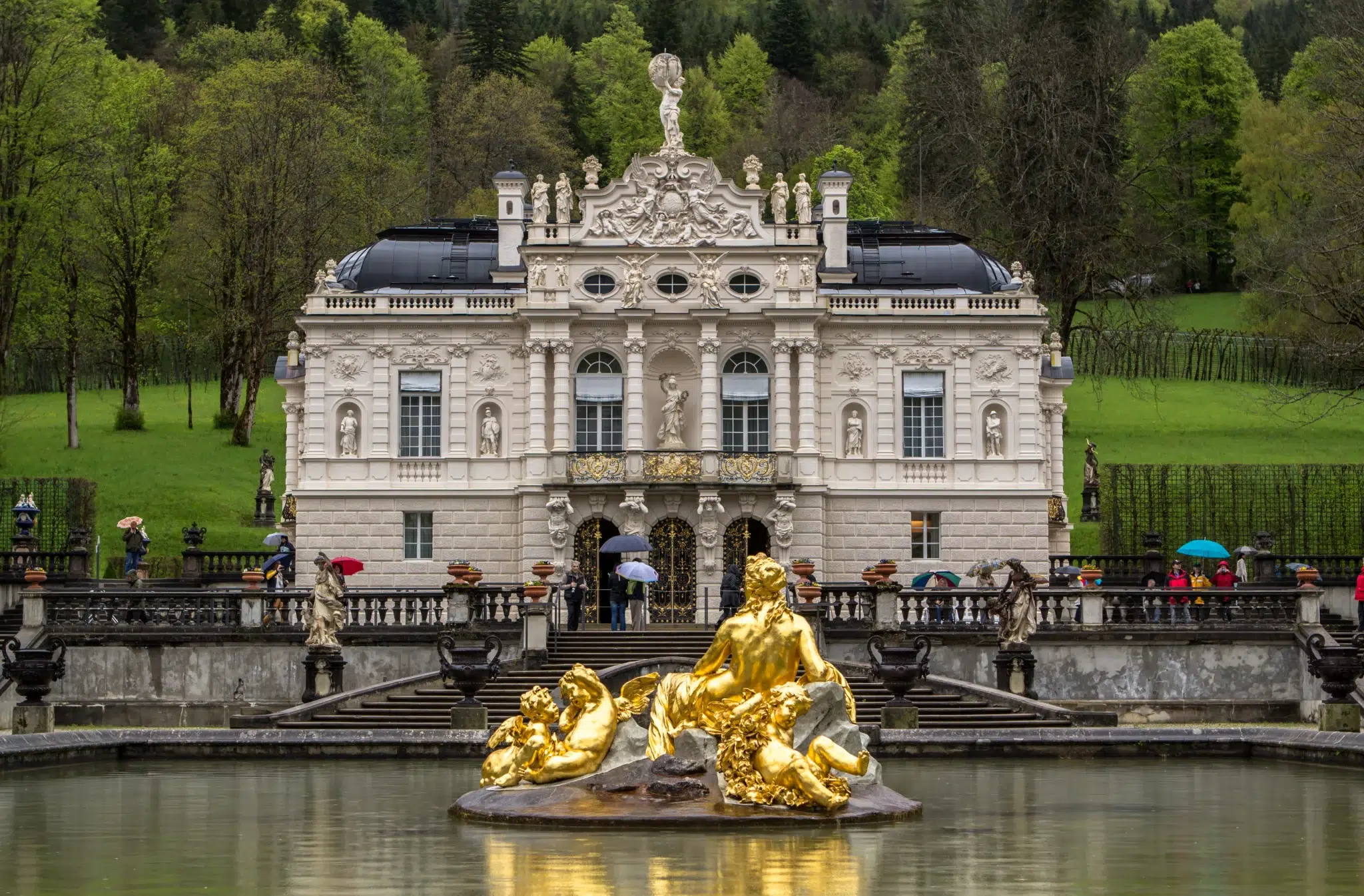 Die Brunnenfiguren in Gold stehen beim Schloss Linderhof hervor trotz regen Wetter.