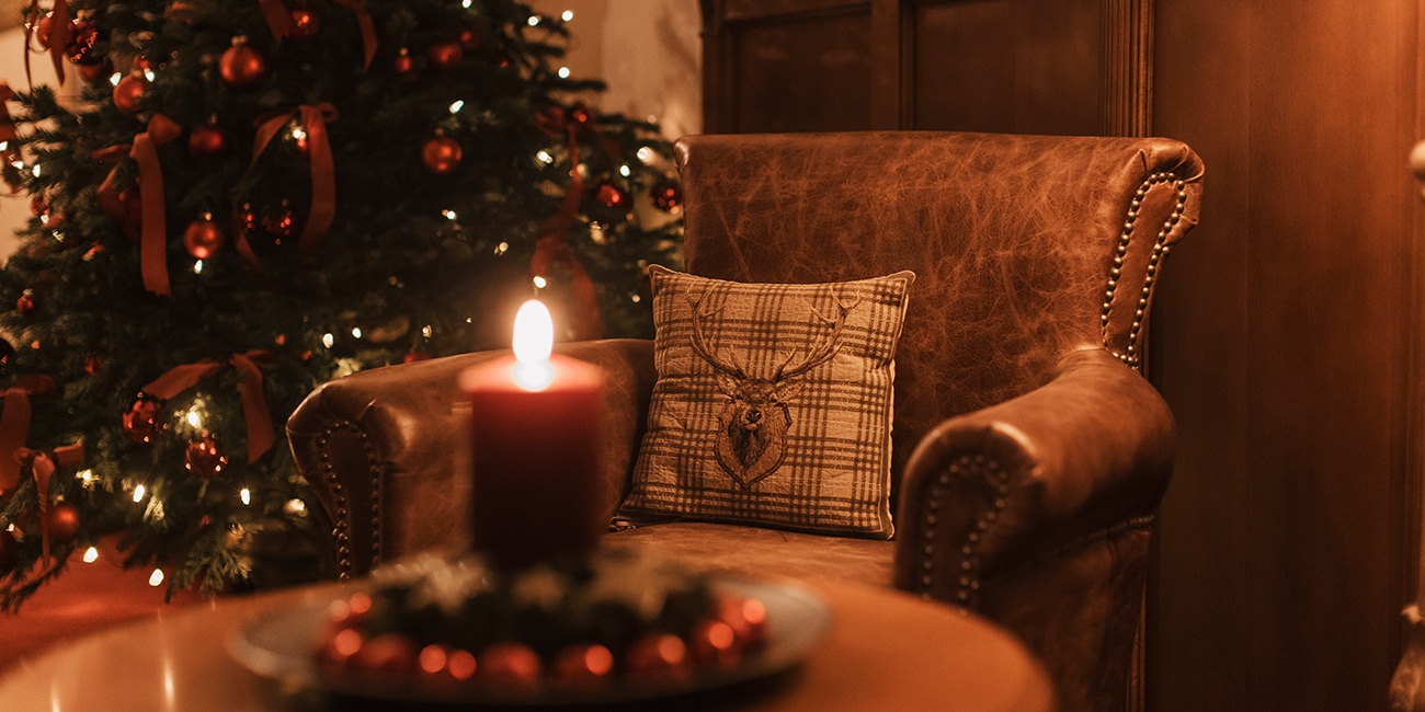 Ein Weihnachtsbaum, der im Hintergrund steht, daneben findet sich ein Lederstuhl